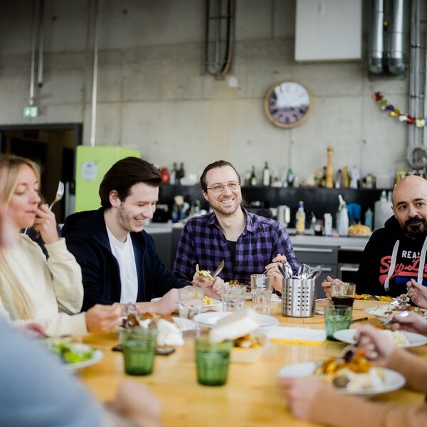 Gruppe von Kollegen genießen gemeinsam eine Mahlzeit in einem lockeren Büro-Pausenraum. | © Photo: Ilja Kagan, 2022