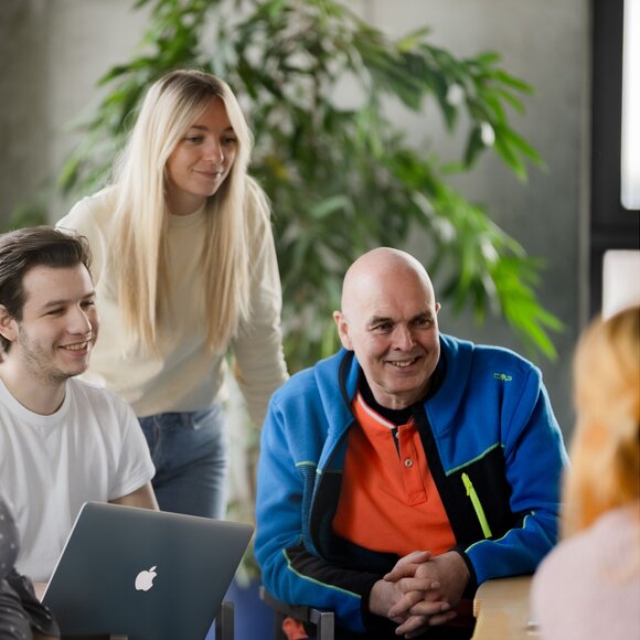 Diverse team of professionals smiling and engaging in a collaborative discussion in a modern office setting.