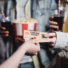 Hand hält ein Kinoticket mit Popcorn und einem Softdrink im Hintergrund. | © Photo: @pressmaster / Freepik Licence