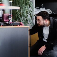 Man observing a 3D printer in operation in a creative office space. | © Photo: Ilja Kagan, 2022