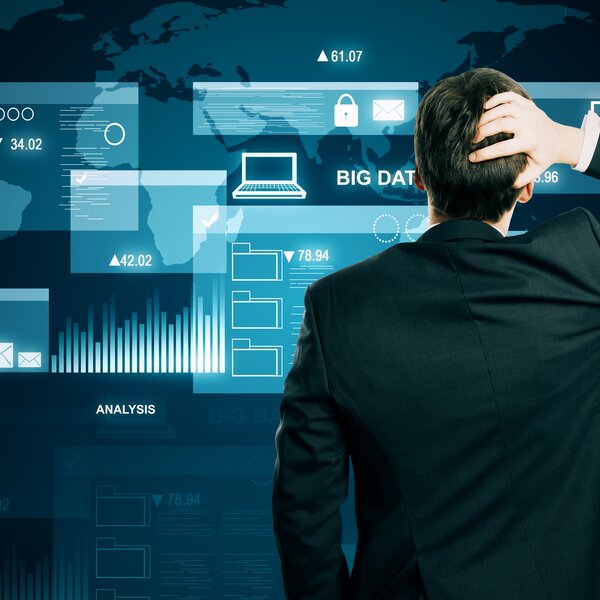 Monitor zeigt digitales Schutzschild mit Schloss und Binärcode, daneben tippt eine Person auf einer Tastatur, im Hintergrund Quellcode.