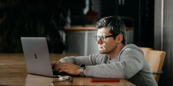 A man is working on a laptop in an office.