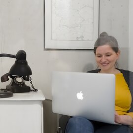 A woman is working on a laptop in an office.