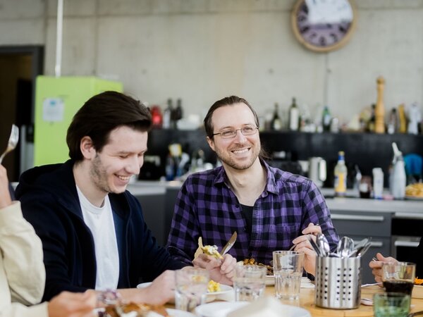 Gruppe von Kollegen genießen gemeinsam eine Mahlzeit in einem lockeren Büro-Pausenraum. | © Photo: Ilja Kagan, 2022