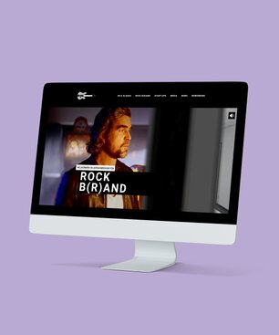 Ein Computermonitor, auf dem eine Rock B(r)and-Kundenreferenz aus dem Portfolio der Krankikom GmbH präsentiert wird.