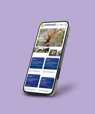 A smartphone on which an Orthomol customer reference from the Krankikom GmbH portfolio is presented.