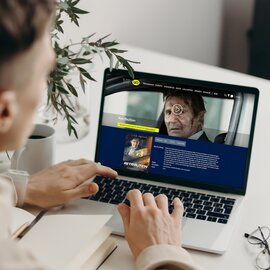 Eine Person benutzt einen Laptop mit einem Bild von UCI Kinowelt Webseite | © Freepik Premium licence @hkwai1012