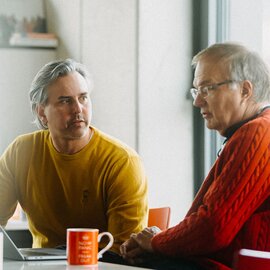 An employee and Alexander Kranki, CEO of Krankikom GmbH, in a discussion over a laptop in the office.